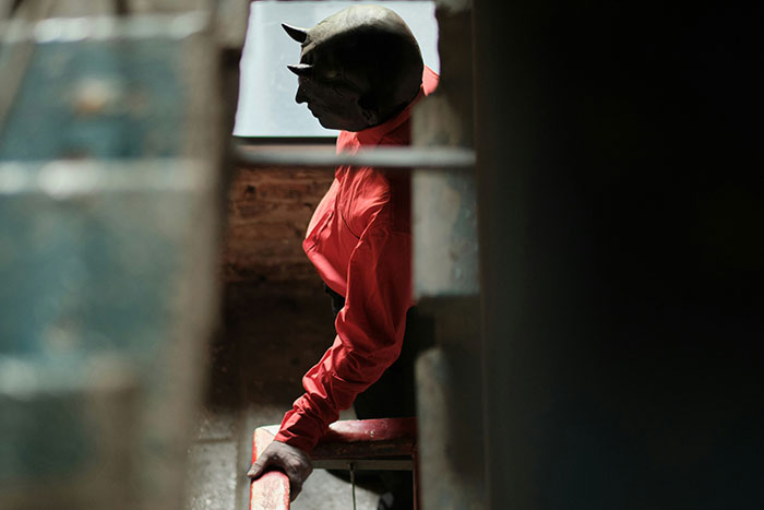 Person wearing a dark horned mask and red shirt in dimly lit room, illustrating terrifying psychosis experiences.