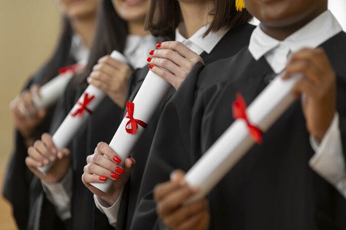 Adults in graduation robes holding diplomas, showing they never moved on from their high school glory days.