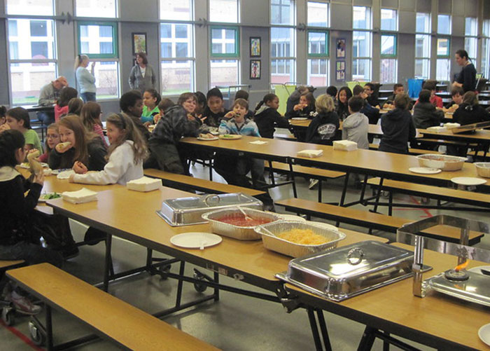 Teenagers in an American school cafeteria eating lunch, showcasing typical American school lunches and dining environment.
