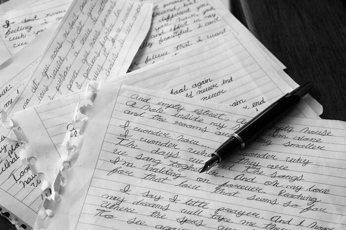 Handwritten letters and a pen on a table revealing disturbing things found after a loved one’s death.