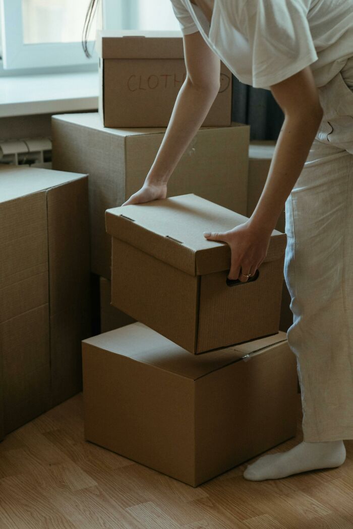 Person unpacking cardboard boxes indoors, symbolizing unexpected and disturbing things found after a loved one’s death.