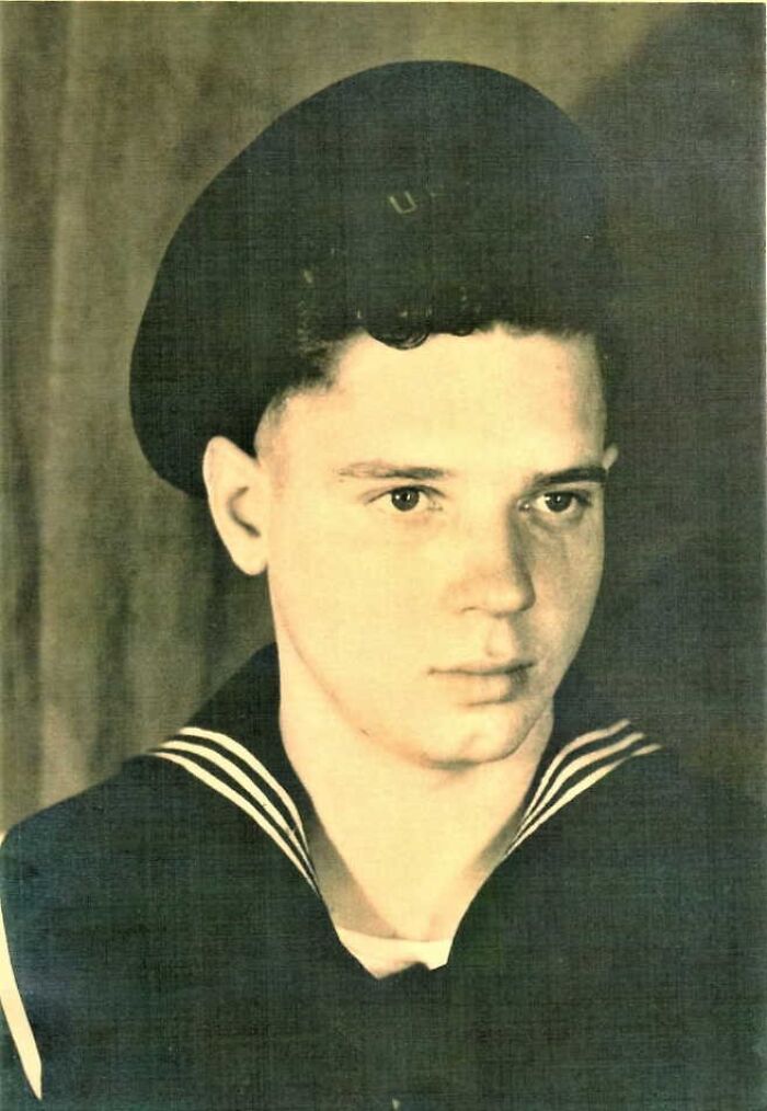 Young man in vintage navy uniform, black sailor hat, looking solemn, related to disturbing things found after a loved one’s death.