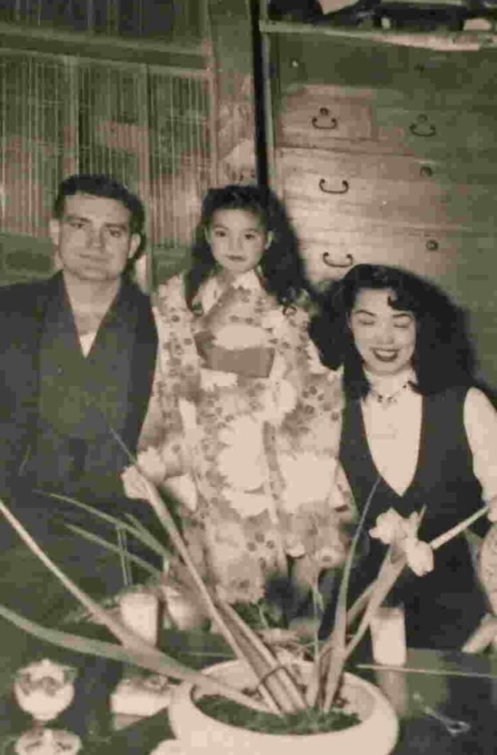 Vintage family photo with three people sitting indoors, evoking themes of discovering disturbing things after a loved one’s death.