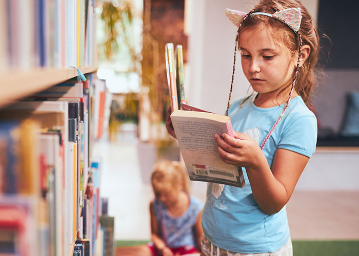 Young girl reading a book in a library, illustrating curiosity and discovery of darkest secrets anonymously shared.
