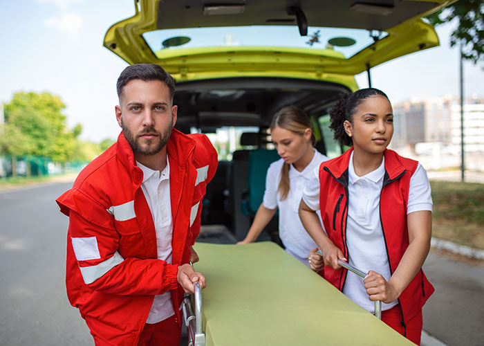 Three emergency responders in red uniforms transporting a stretcher outdoors, illustrating intense and dark secrets shared anonymously.