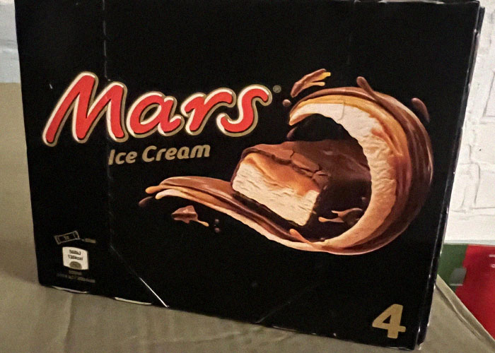 Mars ice cream bar packaging with chocolate and caramel swirl detailed on a black background in close-up view.