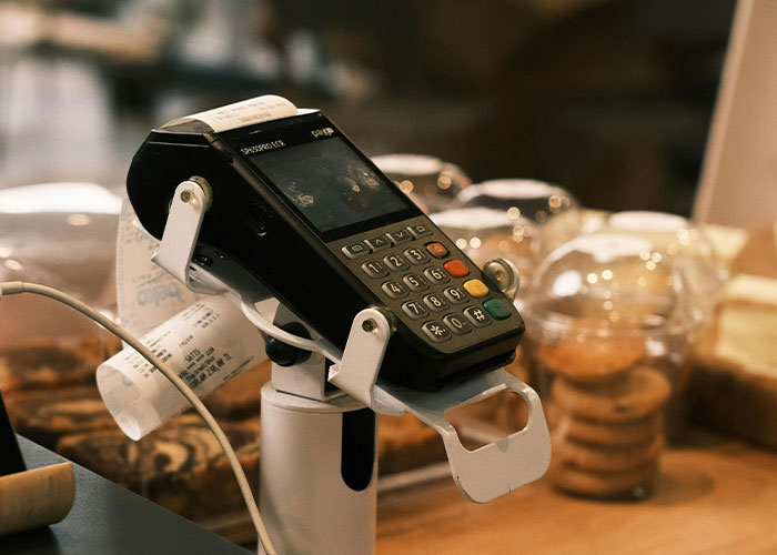 Card payment terminal with printed receipt in a cozy cafe setting related to darkest secrets anonymously shared.