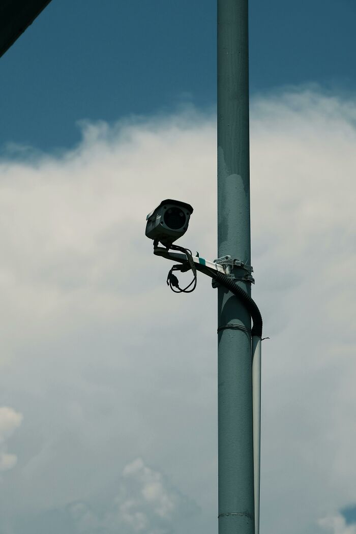 Surveillance camera mounted on pole against cloudy sky, illustrating scary online moments that left people traumatized.