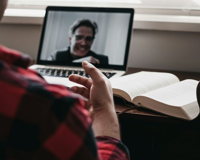 Person in a red plaid shirt gesturing during a virtual call, representing scary online moments that left them traumatized.