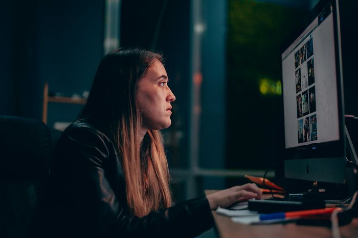 Young woman staring intently at computer screen late at night reflecting scary online moments that left her traumatized.