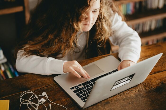 Young person using a laptop at a wooden table, experiencing one of the scary online moments shared by people.