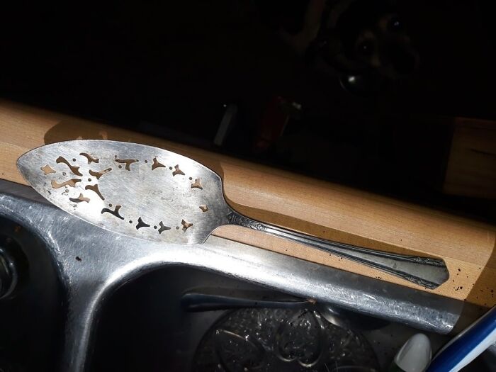 Vintage silver serving utensil with decorative cutouts found in a hidden wall space, surprising and confusing the owner.