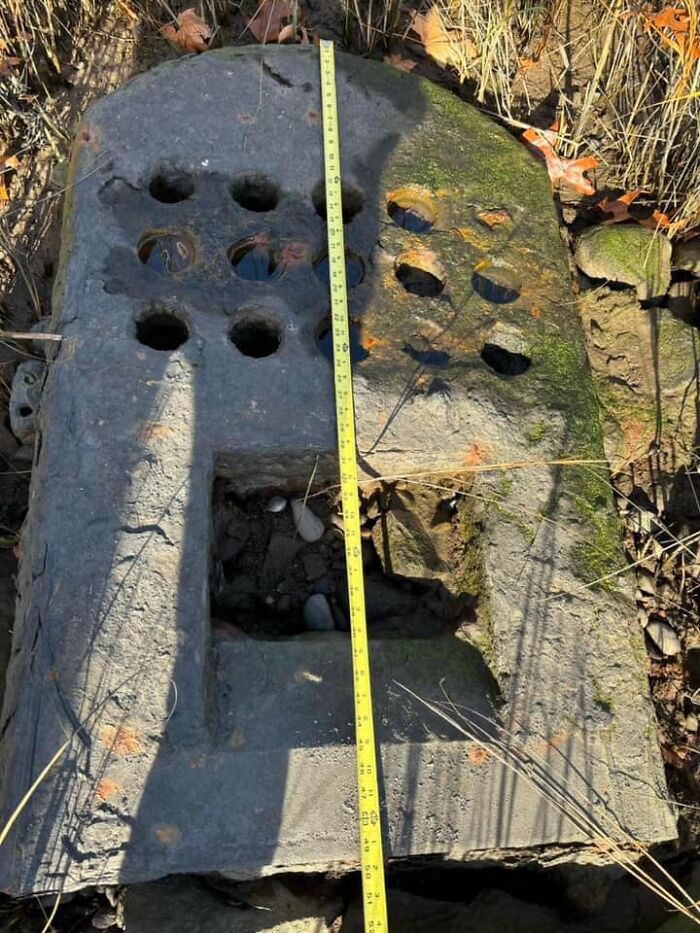 Old concrete slab with circular holes and a rectangular cutout, found outdoors, measuring tape showing its size - things found in walls.