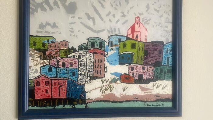 Colorful abstract painting of houses hanging on a wall, an example of things people found in their walls that confused them.