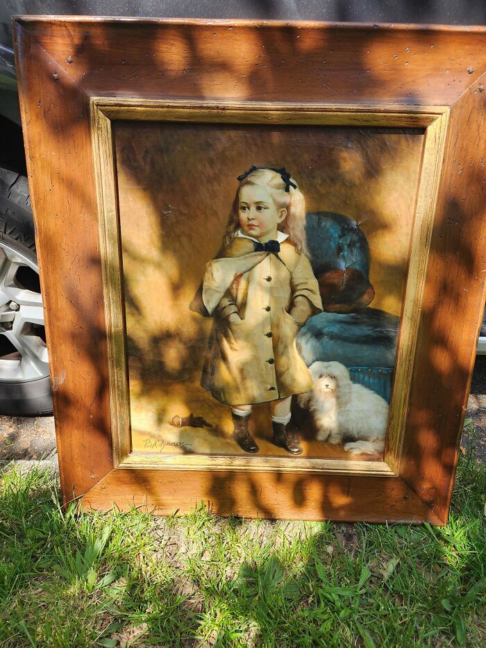 Framed vintage painting of a young girl with a small dog, an unexpected item found in walls or other places.