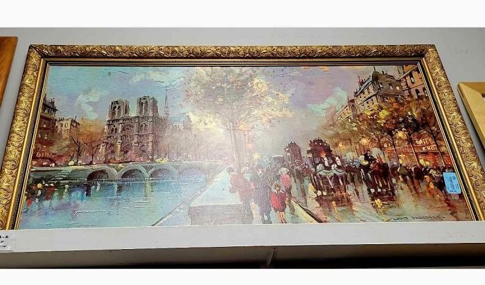 Framed vintage cityscape painting found hidden in a wall, surprising people with an unexpected art discovery.