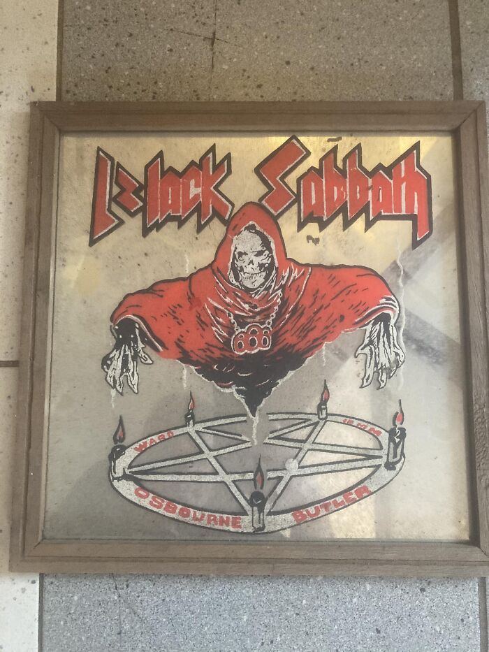 Framed vintage Black Sabbath artwork featuring a grim reaper and pentagram found in walls or other places confusing people.