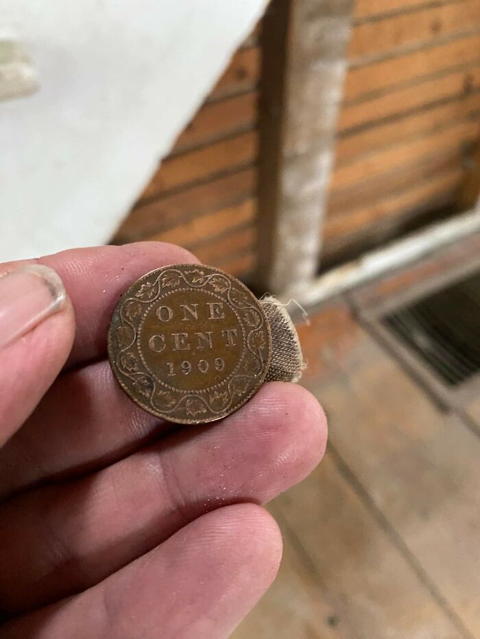 Hand holding a 1909 one cent coin found in walls, one of the things people found that really confused them.