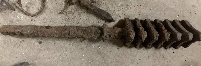Long rusted metal object with multiple large teeth, an unusual item found in walls or other places, puzzling people.