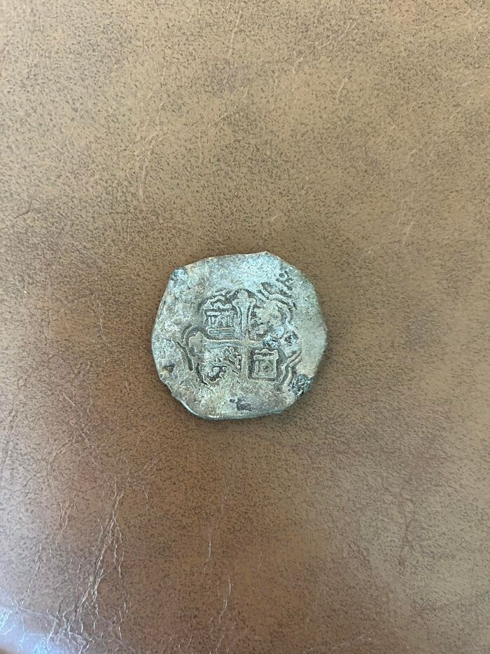 Old worn coin found in walls or other places that really confused people, showing intricate designs and symbols.