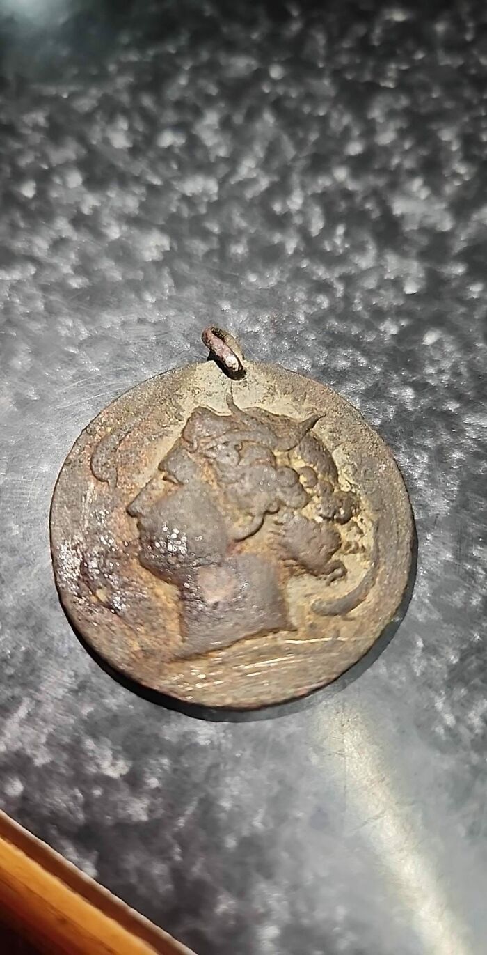 Old worn coin or medallion found in walls or other places that really confused people, showing a profile of a person.
