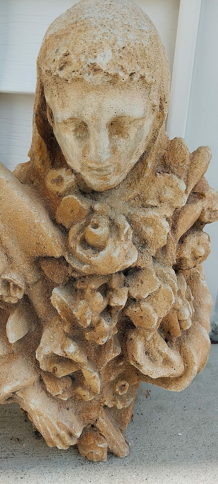 Weathered stone sculpture of a confused face surrounded by abstract shapes found in walls or other places.