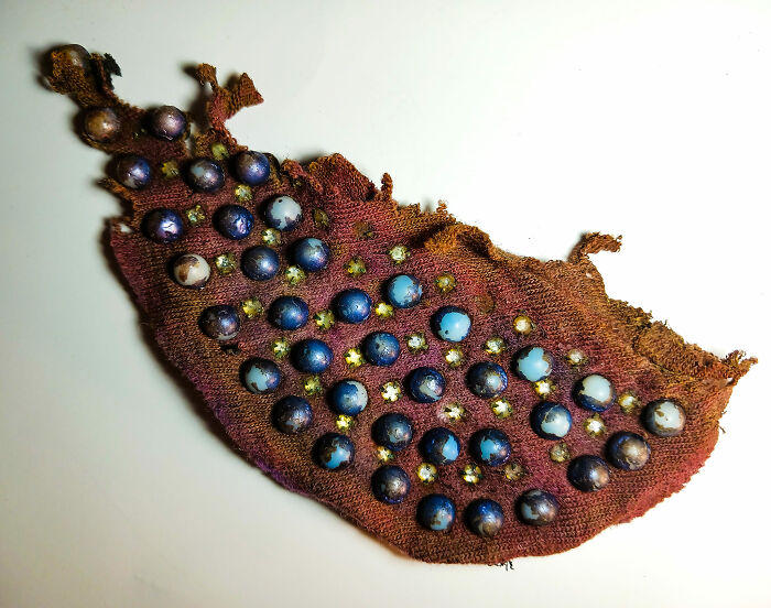 Old fabric with attached blue and white marbles found in a wall, surprising people with unusual hidden items.