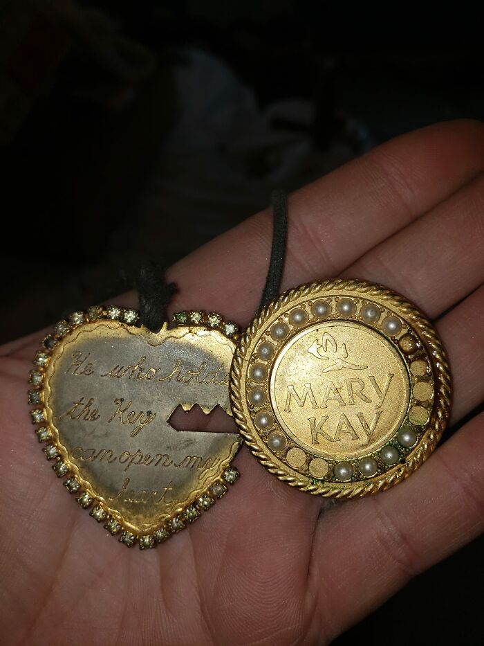 Hand holding vintage Mary Kay compact and heart-shaped key with engraved message found in walls or other places.