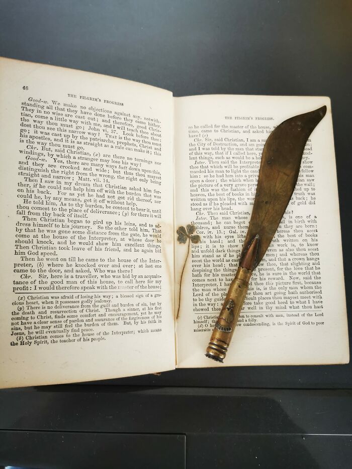 Opened old book with a rusty gardening tool found inside, an unusual discovery that confused many people in their walls or other places.