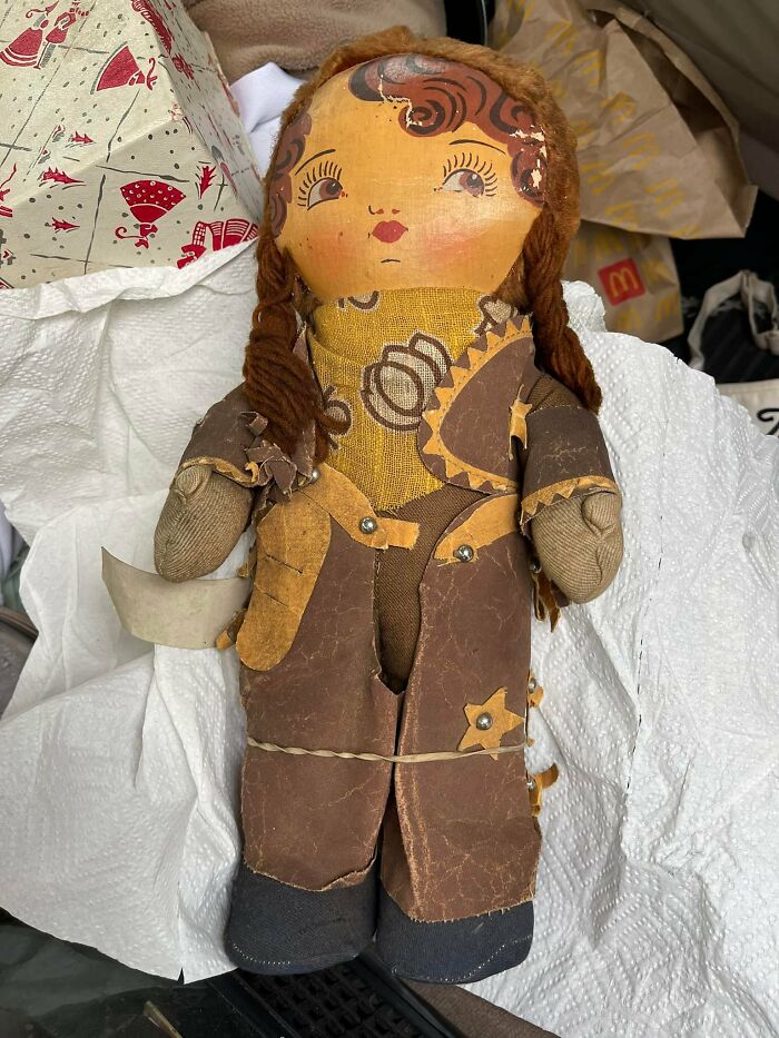 Vintage fabric doll with braided hair and patterned outfit found among other items, a curious discovery in walls or hidden spaces