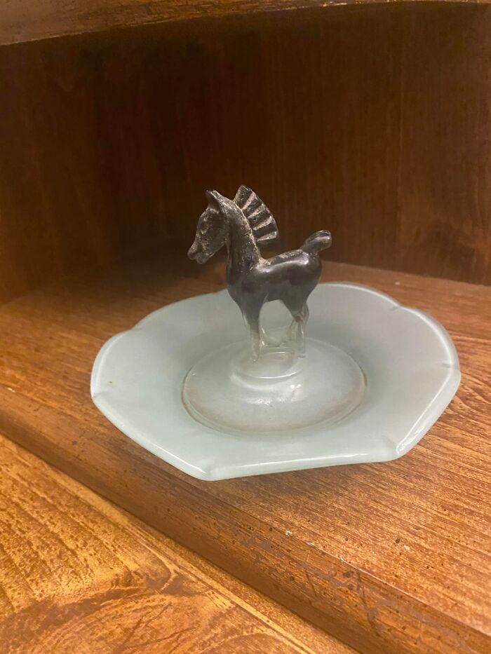 Small horse figurine on a decorative dish found in a wooden cabinet as a confusing unexpected discovery inside walls or places