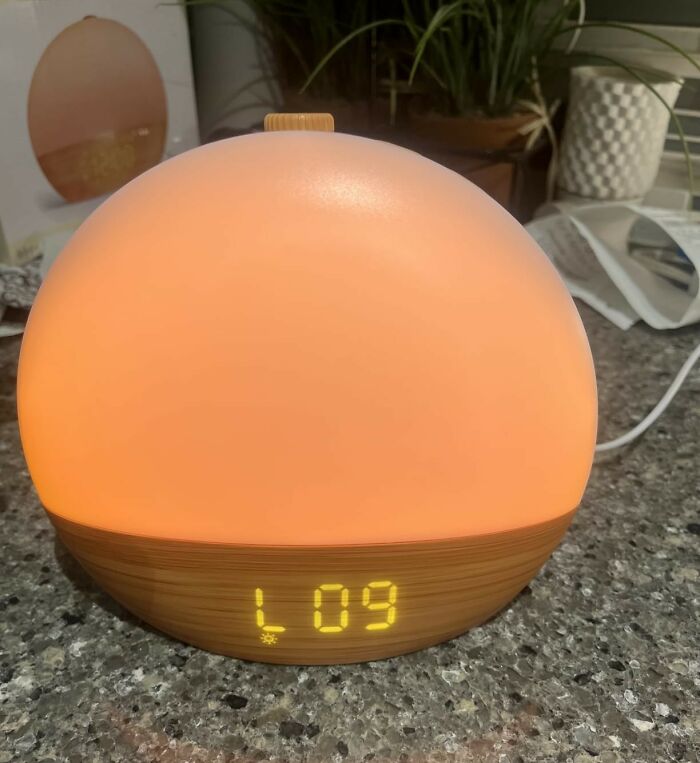 A modern diffuser and clock with soft light on a kitchen countertop showcasing everyday items under 300 dollars.
