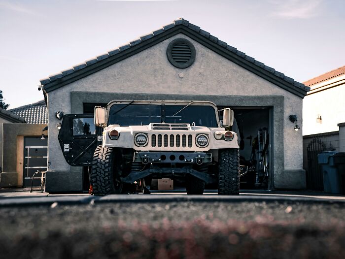 White off-road vehicle parked in a suburban driveway, showcasing middle class lifestyle and typical home setting.