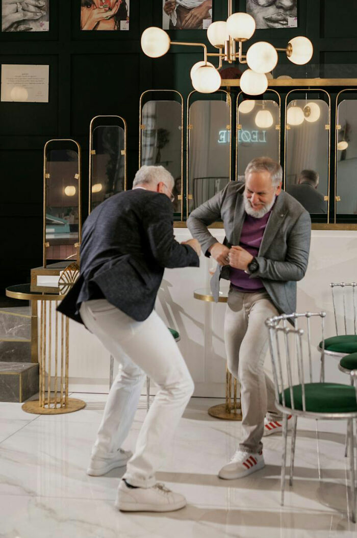 Two men in casual blazers interact playfully in a luxurious private resort setting with modern decor and lighting.