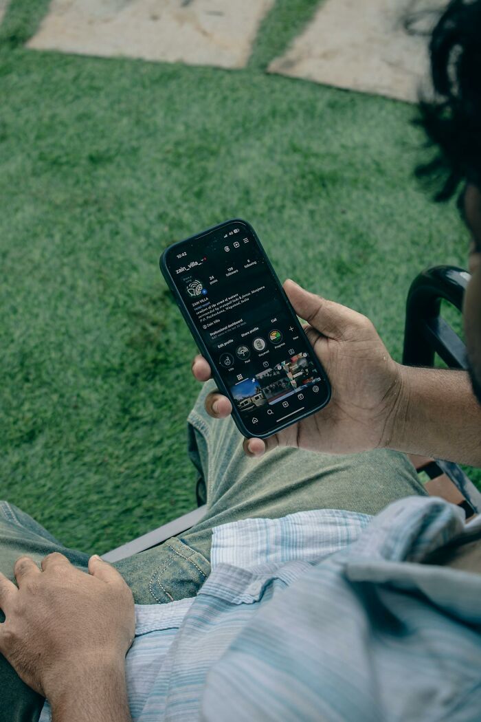 Man scrolling on a smartphone outdoors, illustrating women sharing wildest things they let exes get away with online.