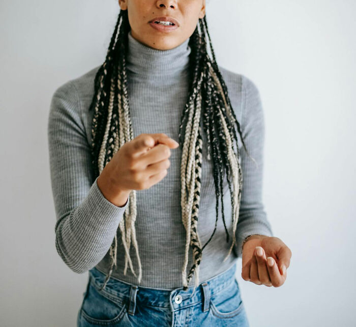 Woman with braided hair wearing gray turtleneck and jeans pointing, illustrating terrible parents revealing true ugly colors.
