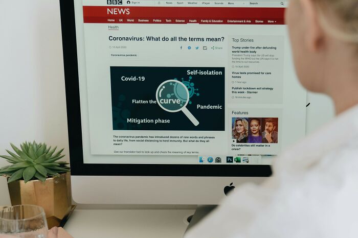 Person viewing BBC News article about coronavirus terms on a desktop computer, related to UK public health discussions.