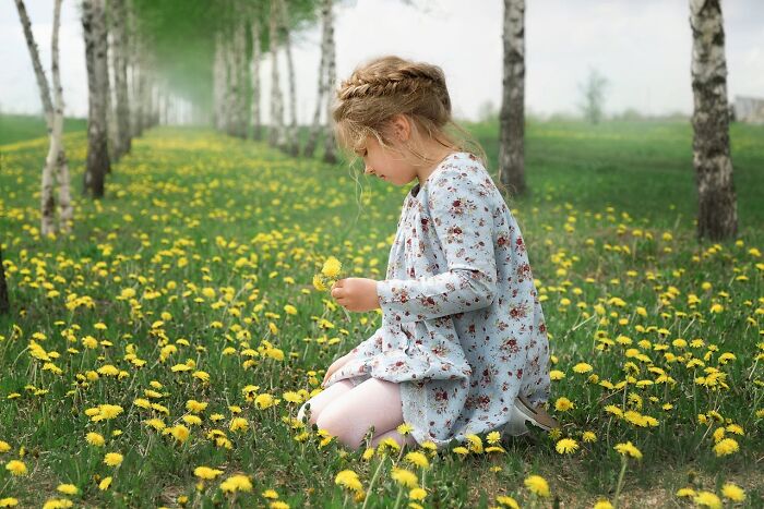 Young girl in floral dress sitting among yellow dandelions, reflecting the impact of worst parents experienced by many.