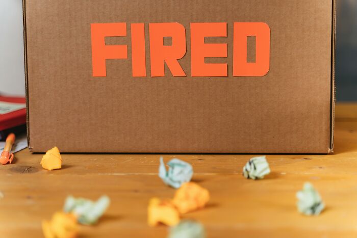 Cardboard box with the word fired on it surrounded by crumpled paper representing companies that crashed after key employees left.
