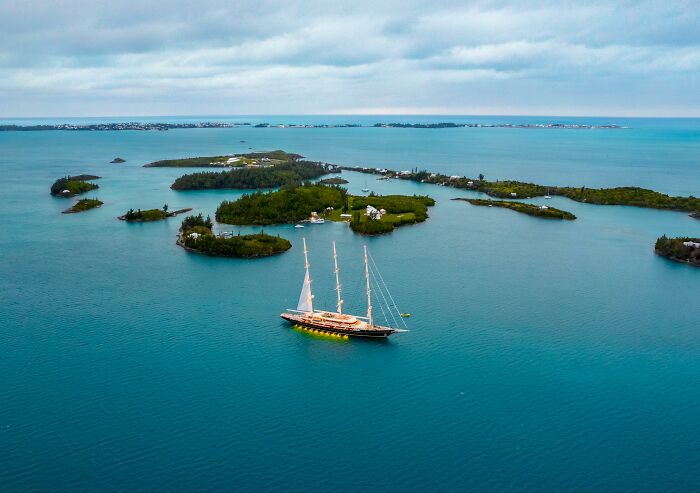 Sailing ship near small islands on calm water under a cloudy sky, evoking mysterious and unsettling Wikipedia articles.