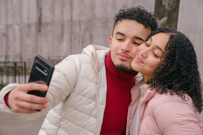 Young couple taking a selfie outdoors, illustrating the wildest things women let their exes get away with.