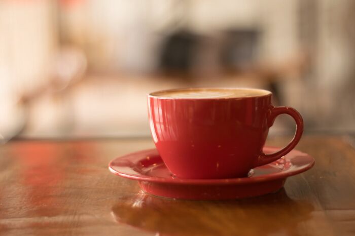 Red coffee cup with saucer on wooden table, symbolizing secrets people feel deeply ashamed to confess to partners.