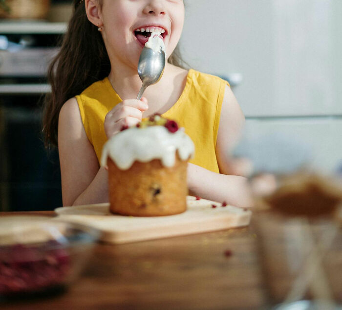Young girl enjoying cake with icing, illustrating innocence and contrast to stories about the worst parents seen.