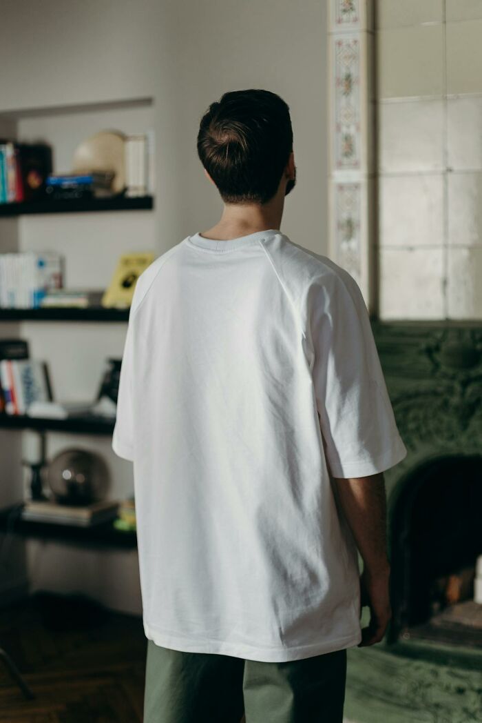 Man in white shirt standing indoors, reflecting on unique childhood joys lost in a life not recorded by smartphones.