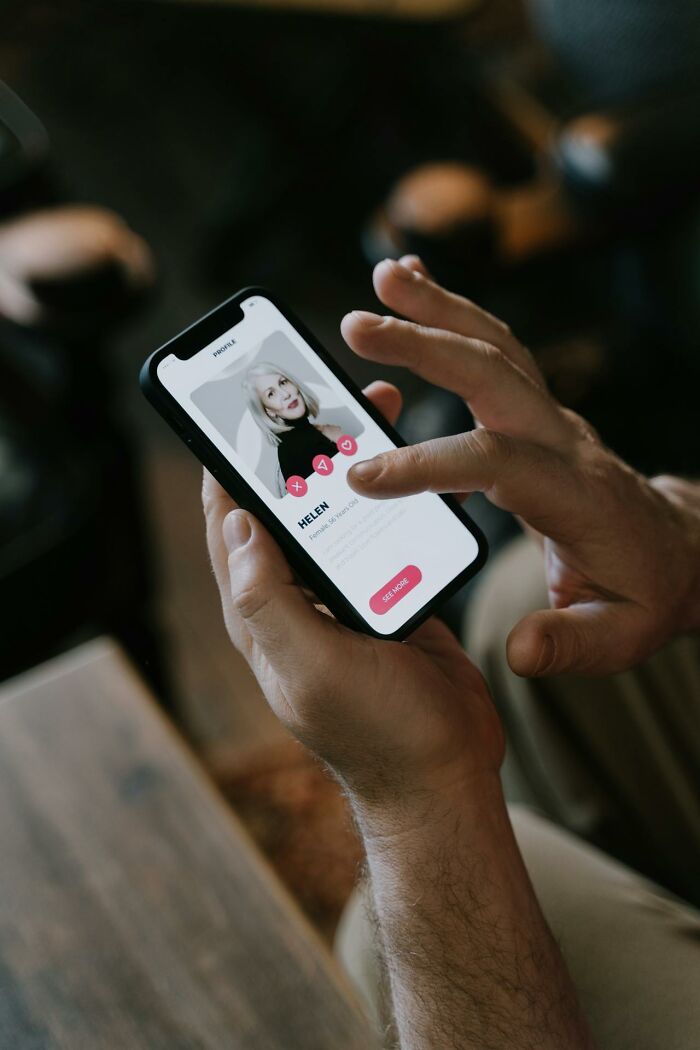 Person holding smartphone and browsing dating app profile, illustrating women sharing wildest things exes get away with.