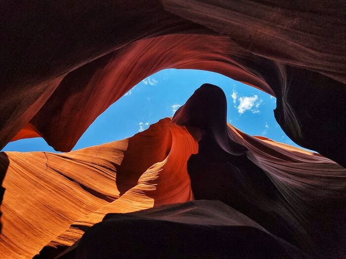 View of a narrow rocky canyon with smooth orange walls and bright blue sky, a travel destination tourists may avoid.