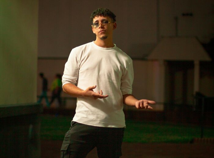 Young man wearing glasses and a white shirt, standing outdoors at night, symbolizing privilege and real world challenges.