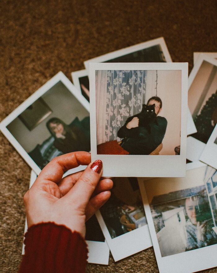 Hand holding a polaroid photo over scattered pictures, symbolizing memories related to wildest things exes got away with.