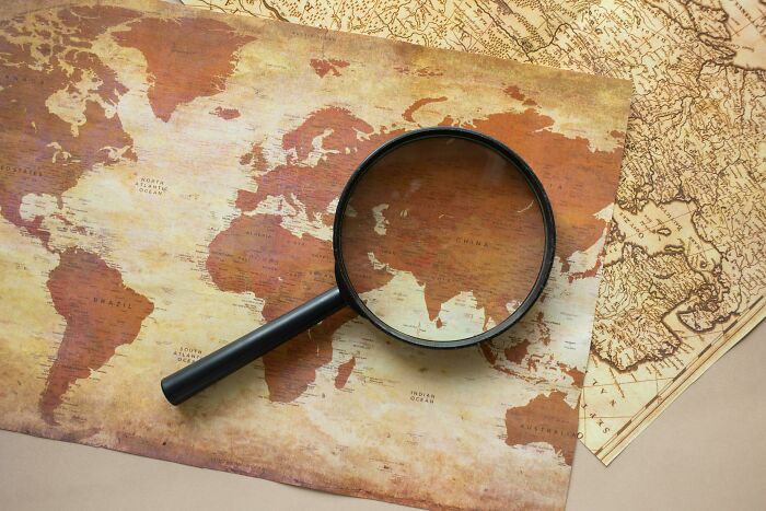 Vintage world map with a magnifying glass focused on Asia, highlighting geography quiz challenge concept.