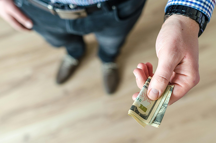 Man in casual clothes holding money, representing a religious couple not paying their babysitter. Man in casual clothes holding money, representing a religious couple not paying their babysitter.